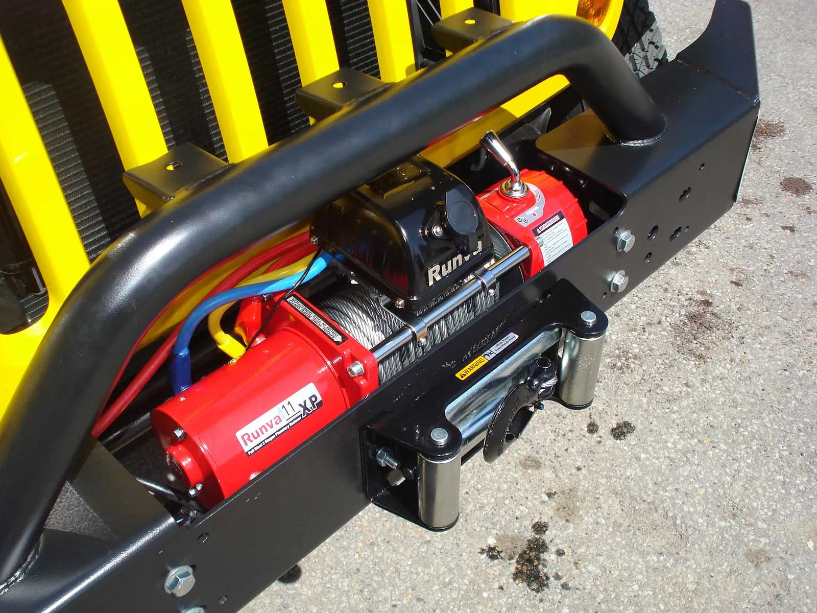 Runvan sähkölvinssi 11xp asennettuna maastoauton keulaan. Vinssissä on aikoillaan vaijeri. Vissi on väriltään punainen.